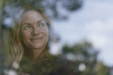 Lächelnde junge Frau hinter Fensterscheibe - GUSF01874