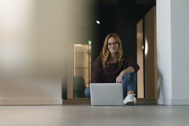 Businesswoman sitting on the floor using laptop - GUSF01879