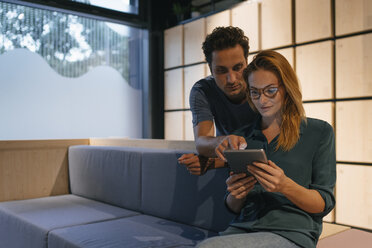 Junger Mann und Frau teilen sich ein Tablet auf der Couch - GUSF01889