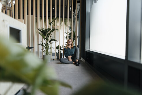 Geschäftsfrau sitzt auf dem Boden in einem modernen Büro - GUSF01912