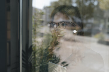 Smiling businesswoman behind windowpane - GUSF01925