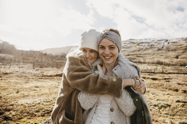 UK, Schottland, glückliche Freundinnen, die sich in einer ländlichen Landschaft umarmen - LHPF00552