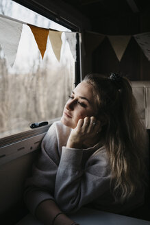 Nachdenkliche junge Frau schaut aus dem Autofenster - LHPF00555