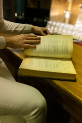 Nahaufnahme einer Frau, die ein altes Buch in einem Vintage-Laden liest - MGOF04014