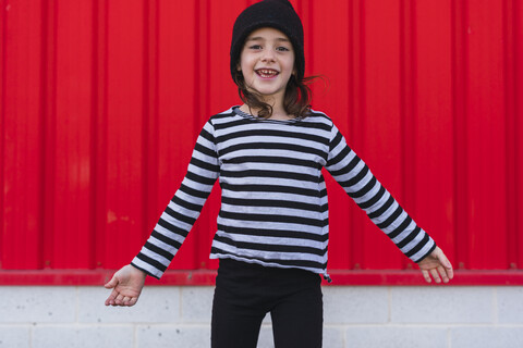 Porträt eines glücklichen kleinen Mädchens mit gestreiftem Hemd und schwarzer Mütze, lizenzfreies Stockfoto
