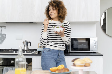 Woman eating strawberries at home - FMOF00586