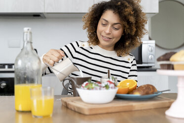 Woman sitting in kitchen, having breakfast - FMOF00587