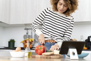 Woman standing in kitchen, preparing salad for lunch - FMOF00605