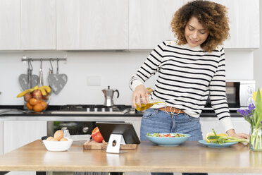 Woman standing in kitchen, preparing salad for lunch - FMOF00607