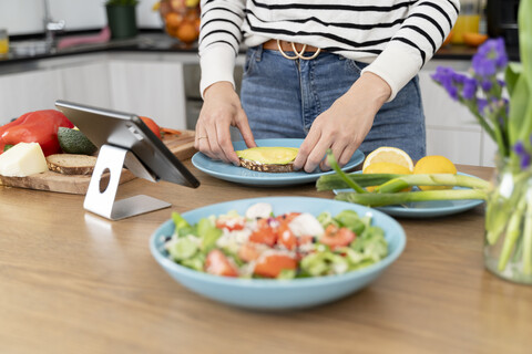 Frau steht in der Küche und bereitet Salat für das Mittagessen vor, lizenzfreies Stockfoto