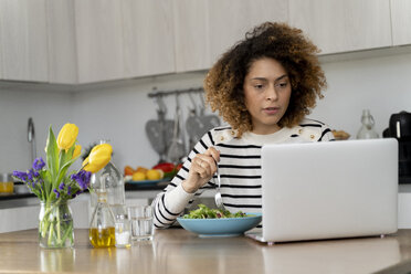 Woman using laptop, eating salad for lunch - FMOF00612