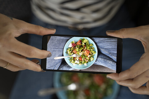 Frauenhände halten Smartphone, fotografieren Salat, lizenzfreies Stockfoto