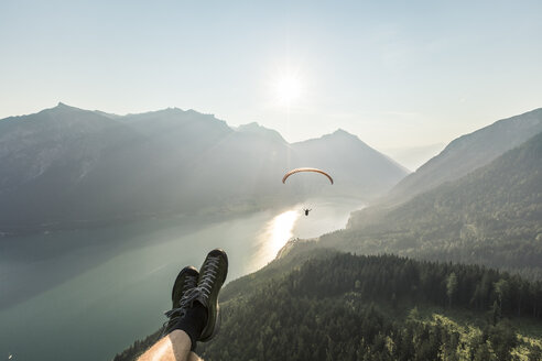 Austria, Tyrol, Legs of a man, watching paraglider over lake Achensee - WFF00083