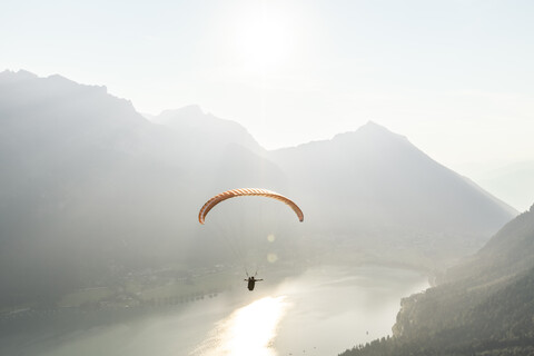 Österreich, Tirol, Gleitschirmflieger über dem Achensee am frühen Morgen, lizenzfreies Stockfoto