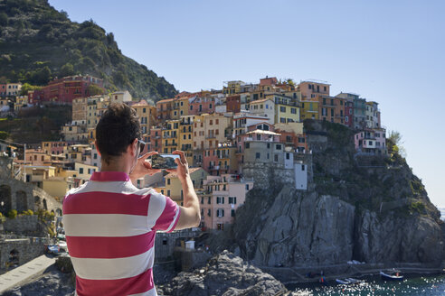 Italy, Liguria, La Spezia, Cinque Terre National Park, man using smartphone, photographing Manarola - EPF00594