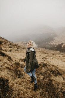 UK, Schottland, Highland, glückliche junge Frau, die in ländlicher Landschaft läuft - LHPF00592