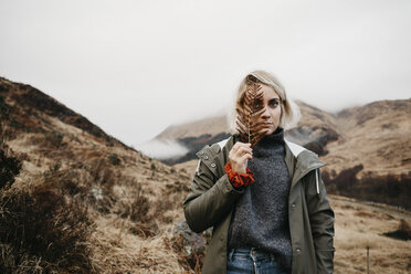 UK, Scotland, Highland, portrait of young woman holding fern - LHPF00600