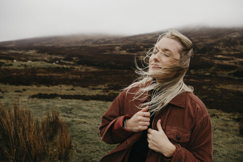 UK, Scotland, Highland, portrait of young woman with windswept hair in rural landscape - LHPF00620