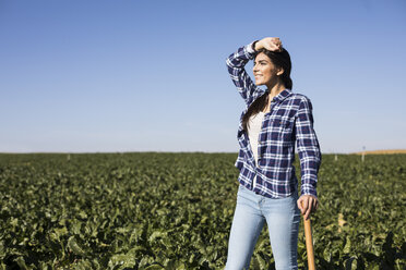 Young woman farmer with hoe on field - ABZF02317