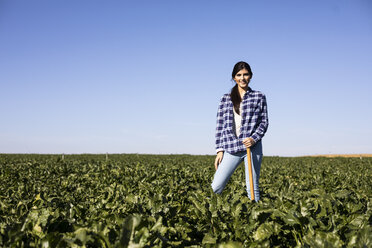 Young woman farmer with hoe on field - ABZF02318