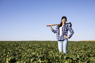 Young woman farmer with hoe on field - ABZF02320