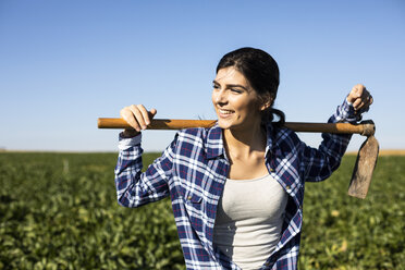 Young woman farmer with hoe on field - ABZF02323