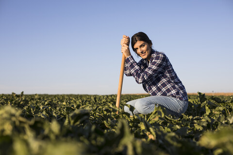 Junge Bäuerin mit Hacke auf dem Feld, lizenzfreies Stockfoto