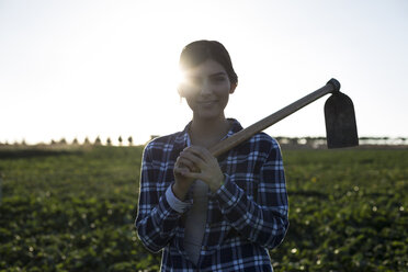 Young woman farmer with hoe on field - ABZF02337