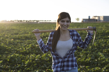 Young woman farmer with hoe on field - ABZF02339