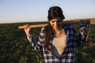 Young woman farmer with hoe on field - ABZF02341