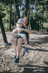 Glückliche Mutter mit kleiner Tochter auf der Schaukel auf einem Spielplatz - DWF00393