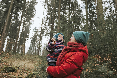 Mutter trägt glückliche kleine Tochter im herbstlichen Wald, lizenzfreies Stockfoto