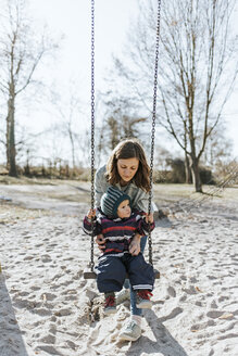 Mutter mit kleiner Tochter auf der Schaukel auf einem Spielplatz - DWF00413