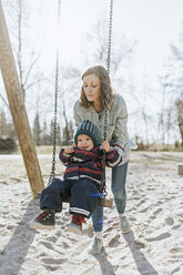 Mutter mit kleiner Tochter auf der Schaukel auf einem Spielplatz - DWF00414