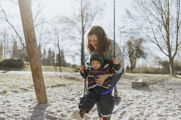 Mutter mit kleiner Tochter auf der Schaukel auf einem Spielplatz - DWF00415