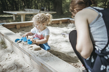 Mutter spielt mit kleiner Tochter im Sandkasten auf einem Spielplatz - DWF00436