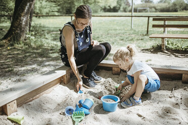 Mother playing with little daughter in sandbox on a playground - DWF00440