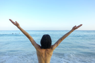 Seychellen, Rückenansicht eines Mannes mit erhobenen Armen vor dem Meer - NDF00891