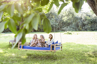 Frauen einer Familie entspannen sich im Garten, sitzen auf einem Schaukelbett - PESF01608