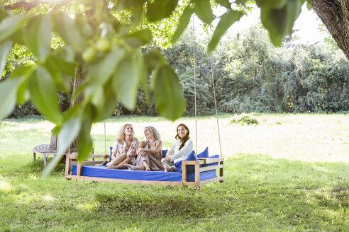 Frauen einer Familie entspannen sich im Garten, sitzen auf einem Schaukelbett - PESF01608