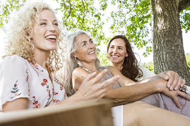 Frauen einer Familie entspannen sich im Garten, sitzen auf einem Schaukelbett - PESF01610