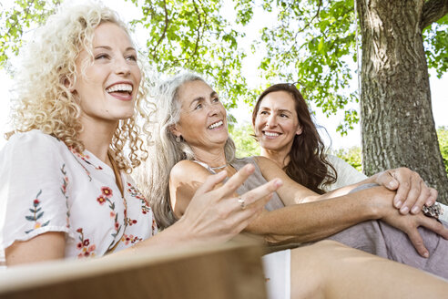 Women of a family relaxing in garden, sitting on a swing bed - PESF01610