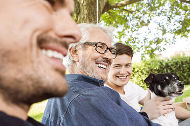 Männer einer Familie, die auf einem Schaukelbett im Garten sitzen und sich unterhalten - PESF01625