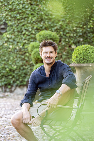 Mid adult man sitting in his lush garden stock photo