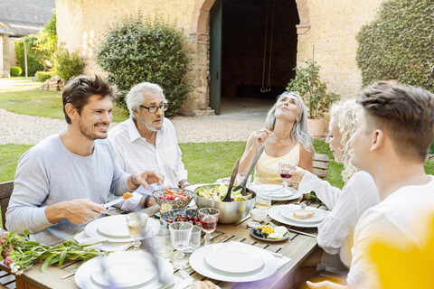 Glückliche Familie beim gemeinsamen Essen im Garten, lizenzfreies Stockfoto