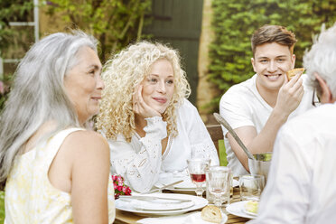 Glückliche Familie beim gemeinsamen Essen im Garten - PESF01642