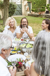 Glückliche Familie beim gemeinsamen Essen im Garten - PESF01650