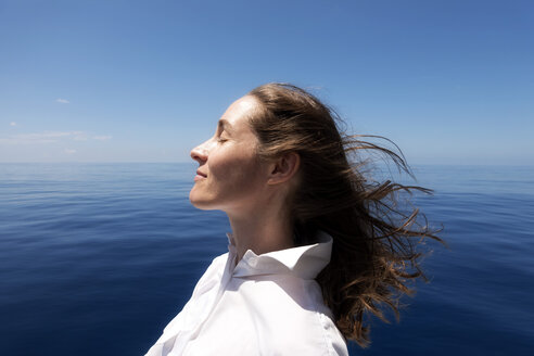 Seychelles, Indian Ocean, profile of woman on ferry enjoying breeze - NDF00907