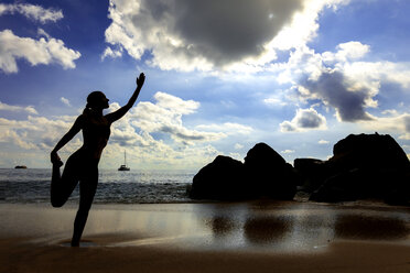 Seychellen, Mahe, Takamaka Beach, Silhouette einer Frau beim Yoga am Strand - NDF00913