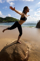 Seychellen, Mahe, Takamaka Beach, Frau macht Yoga auf einem Felsen - NDF00914